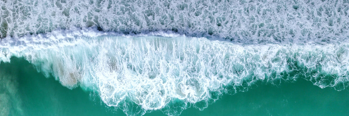 Vue aérienne d’une vague d’écume blanche sur l’océan turquoise, côte bretonne